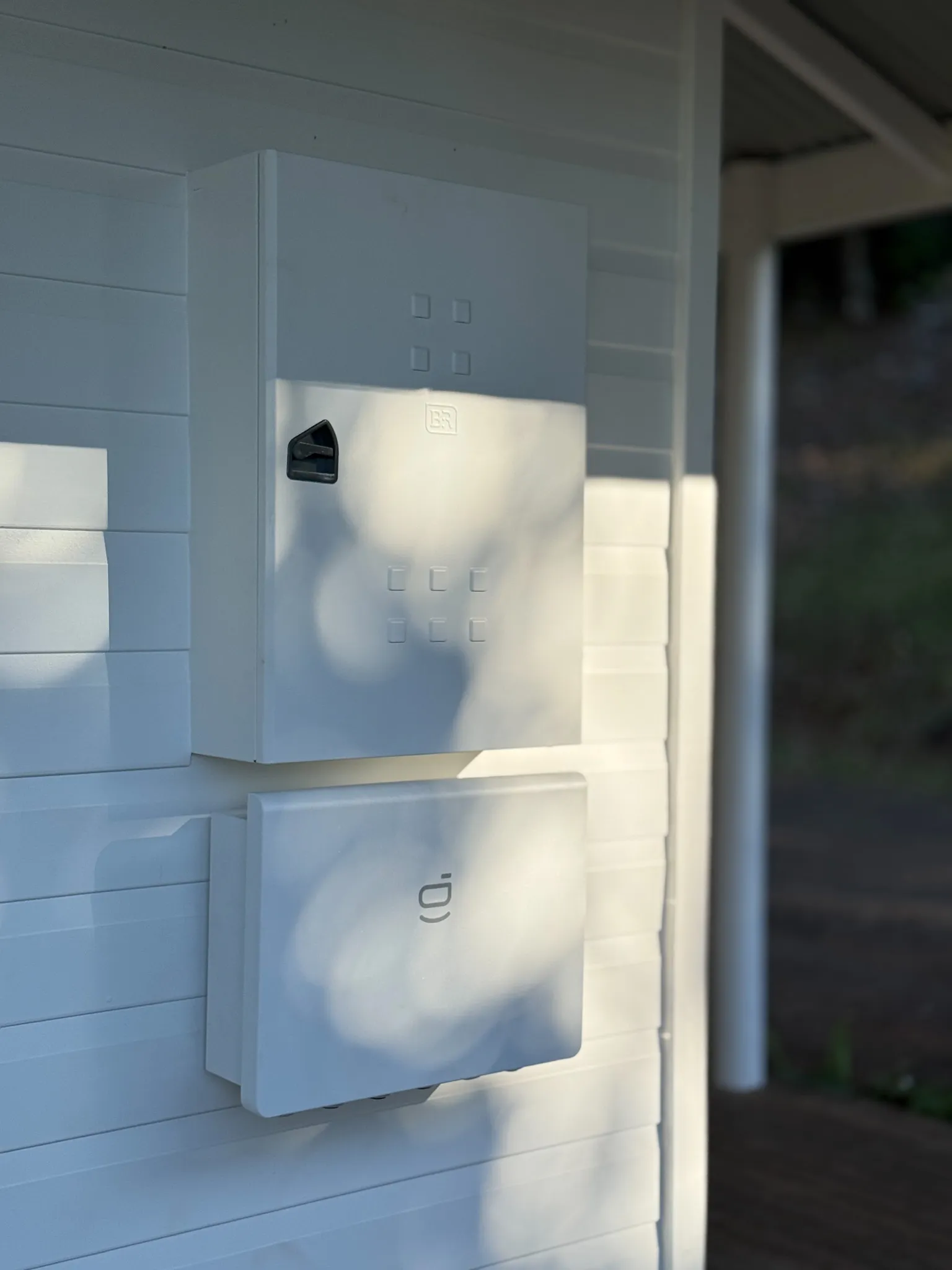 A main switchboard and meter enclosure mounted on the weatherboard wall of a building.